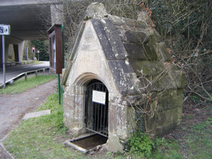 A small stone building with a small doorway and a shallow stone trough