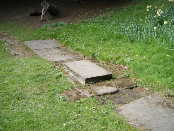 A stone slab covering a spring in a patch of clipped grass
